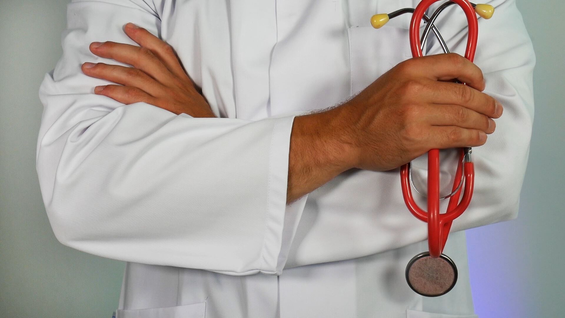 A person in a white coat holding a red stethoscope